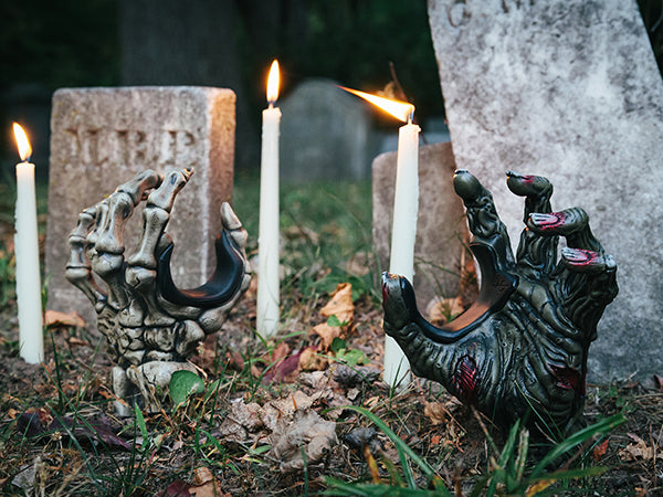 zombie hand and skeleton hand guitar hangers sticking out of the ground in cemetery 