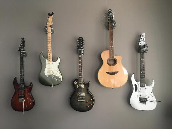 Guitars hanging on the wall. Gibson Les Paul, Fender Stratocaster. 