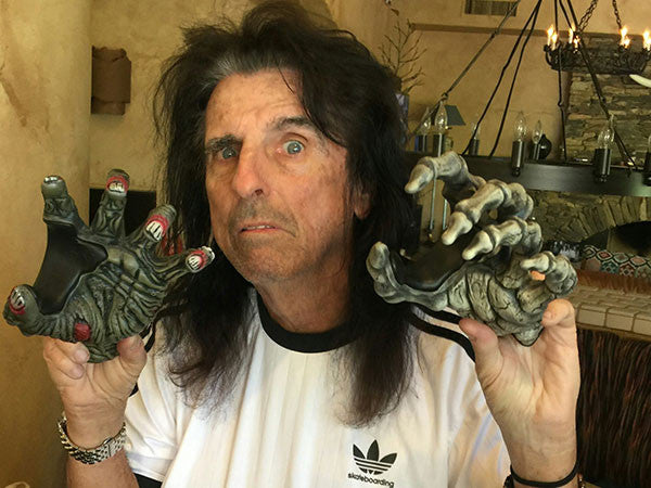 Alice Cooper holding a zombie and a skeleton guitar hangers