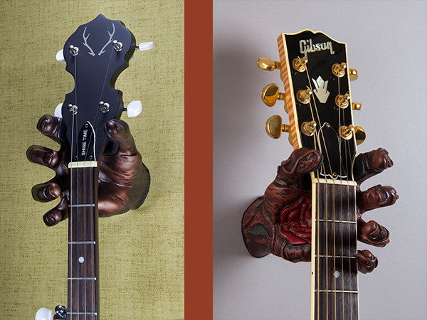 Banjo and Gibson acoustic guitar hanging from hand shaped acoustic guitar hangers