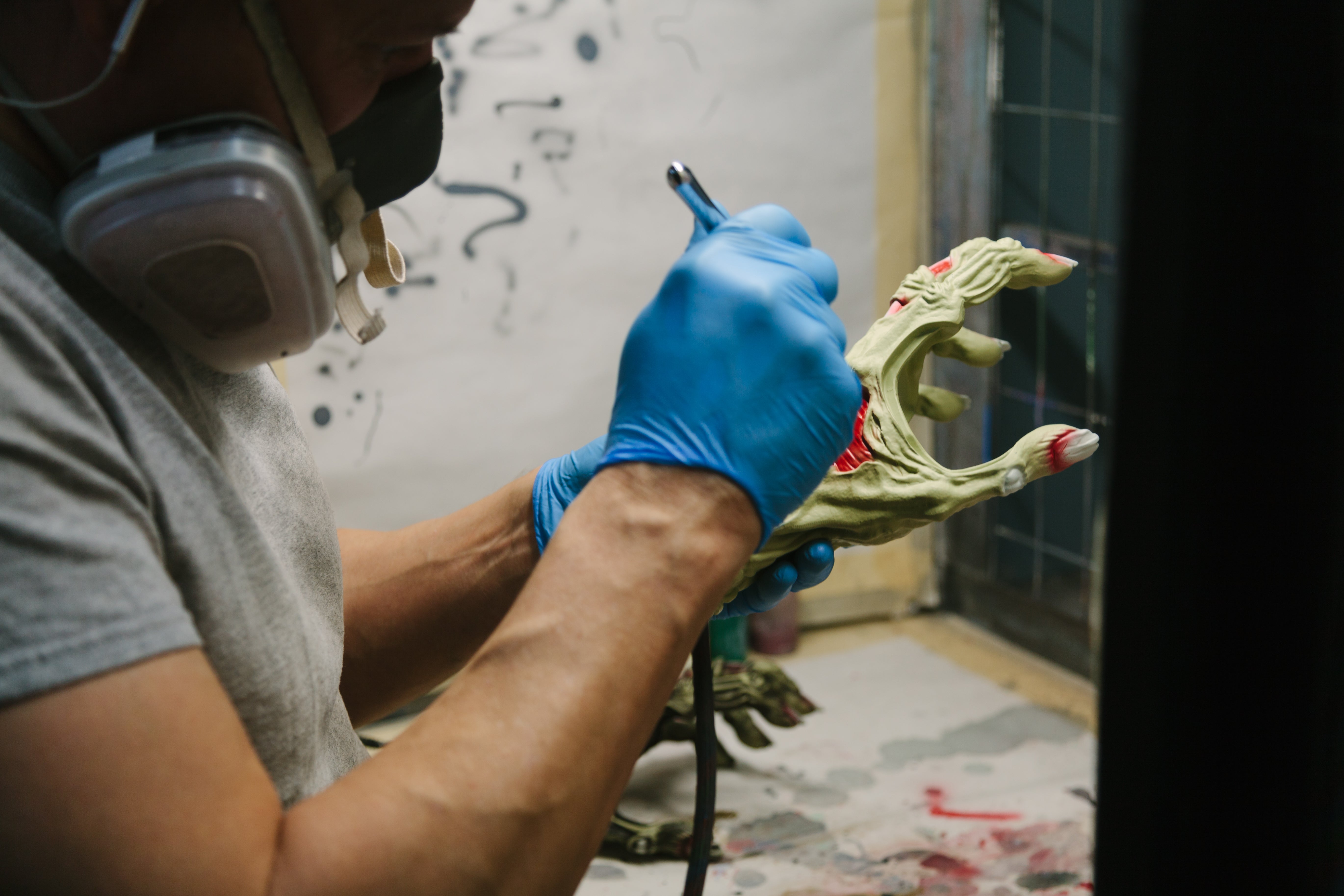 Man airbrushing hand shaped guitar hanger made in the usa. 