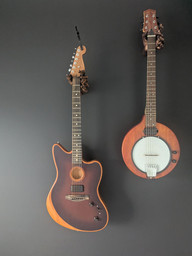 Guitars hanging on the wall with hand shaped guitar hangers.