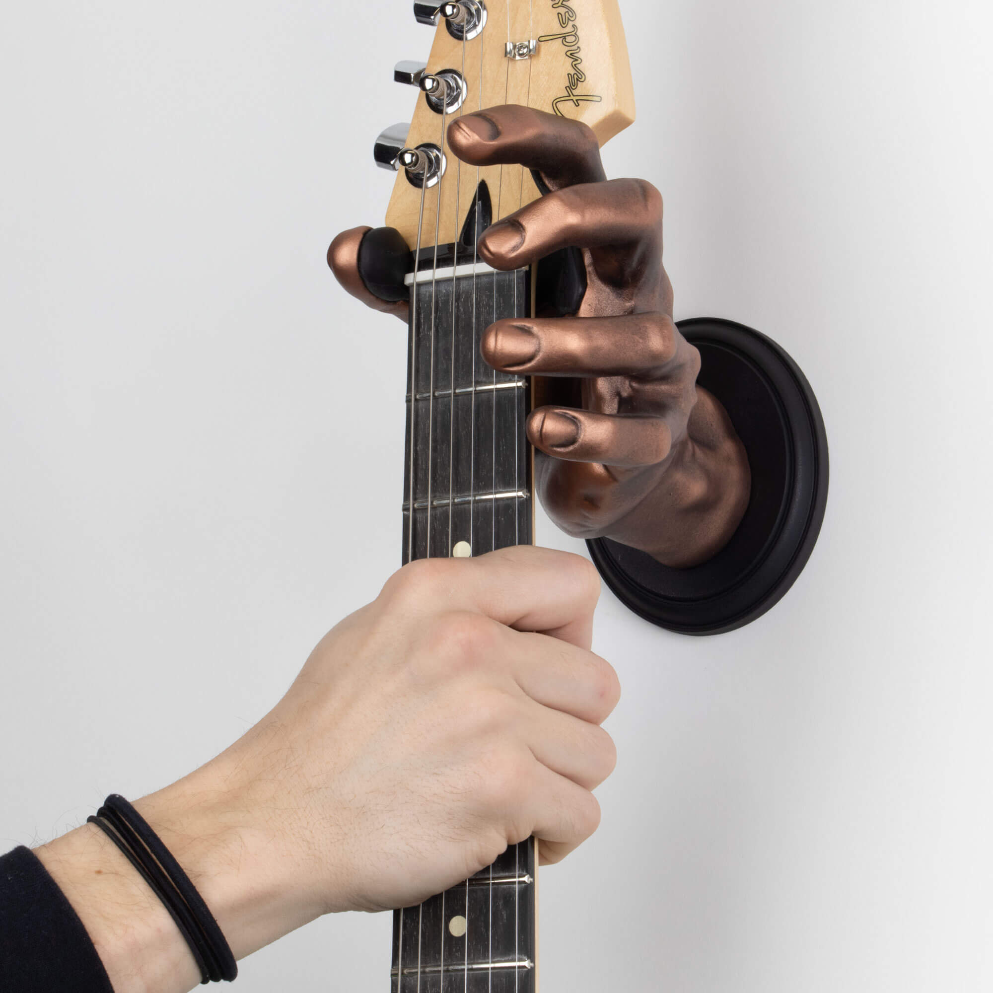 Copper guitar hanger wall mount shaped like a hand on white background. 