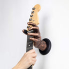 Copper hand guitar wall mount holding guitar.