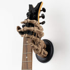 Skeleton hand guitar hanger holding electric guitar on the wall with white background.